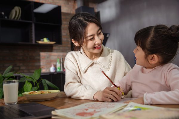 Young mother helping her daughter while she does her homework